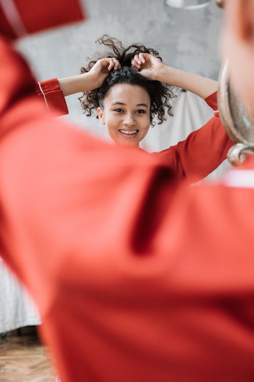 Free Pretty Woman Fixing Her Hair in Front of the Mirror Stock Photo