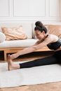 Woman Stretching Her Leg While Sitting on Gray Rug