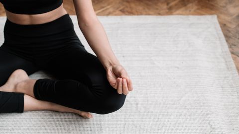 A person meditating indoors, emphasizing relaxation and mindfulness.