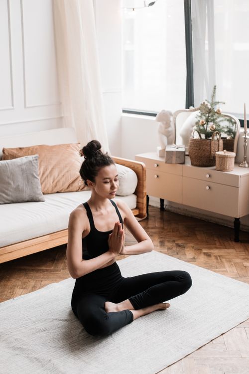Free Woman practicing yoga in a serene living room setting, promoting wellness and relaxation. Stock Photo