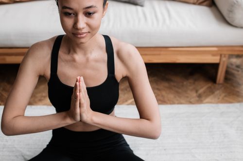 Free A woman in activewear meditating indoors, embodying peace and relaxation. Stock Photo