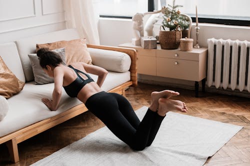 Free Young Woman in Black Sports Bra and Black Leggings Doing Home Workout Stock Photo