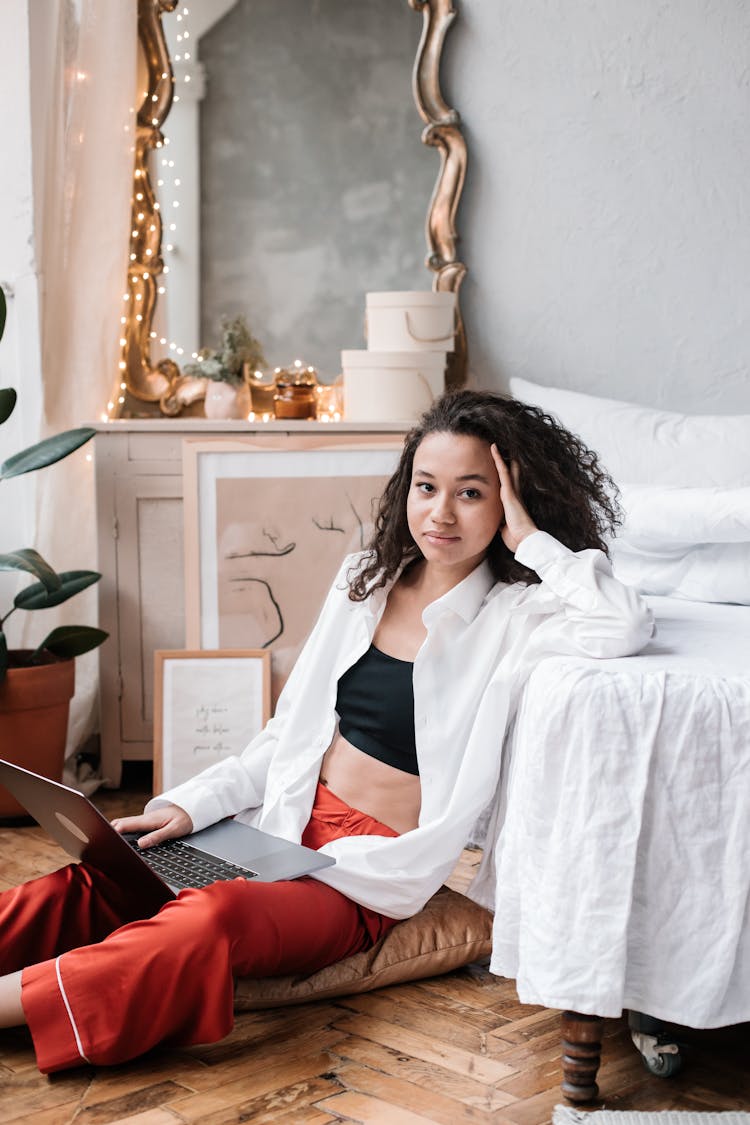 Woman Sitting On Throw Pillow While Leaning On Bed