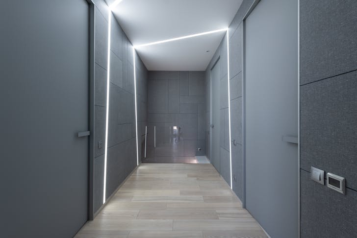 Interior of contemporary hallway of creative space with parquet and gray walls with doors and modern bright illumination on ceiling and walls
