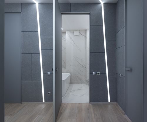 Free Stylish corridor with gray wall and backlight with opened door of modern bathroom with bathtub and tile in contemporary flat Stock Photo