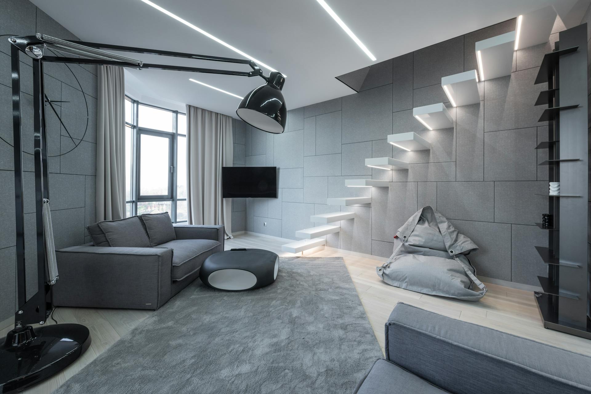 Living room interior with couch near table on carpet near lamp and bean bag chair near TV and steps near window