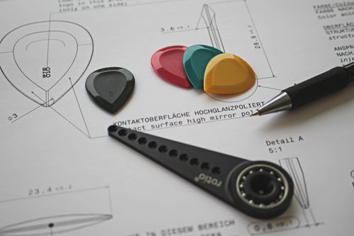 Free Colorful guitar picks on a technical design blueprint with pen and tool. Stock Photo