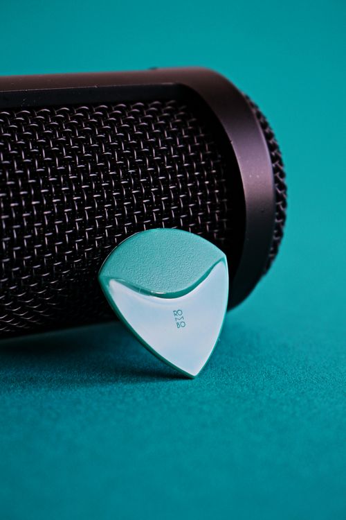 Free Detailed view of a microphone with a green guitar pick on a vibrant surface. Stock Photo