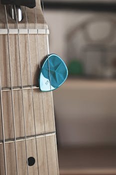 Detailed view of guitar strings and blue plectrum, perfect for music themes.