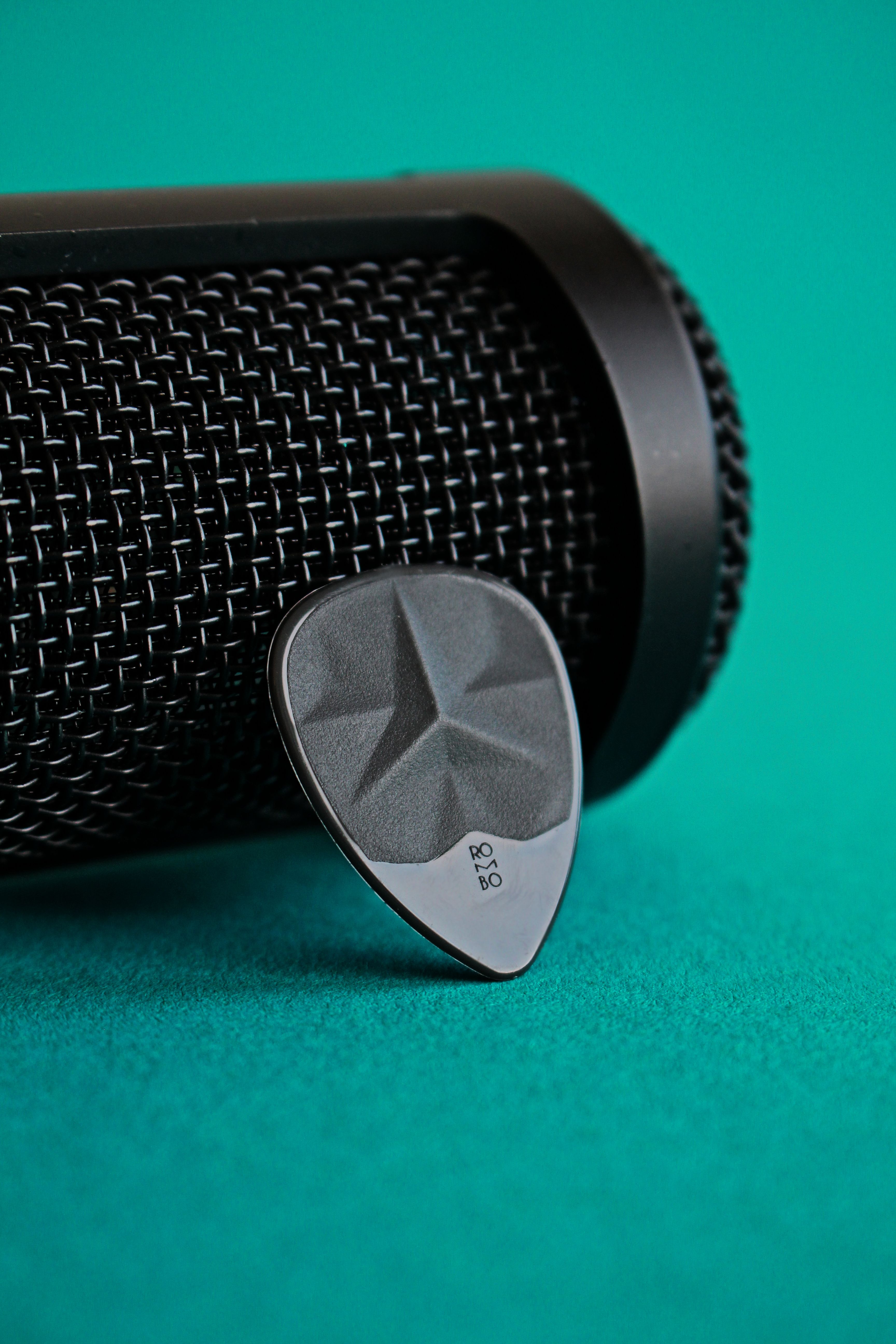 Close-up of a guitar pick and microphone on a vibrant green background, ideal for music concepts.