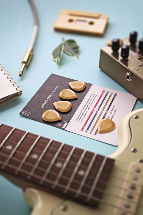 Free A detailed shot of guitar picks, pedal, and cable on a light blue surface, perfect for music enthusiasts. Stock Photo