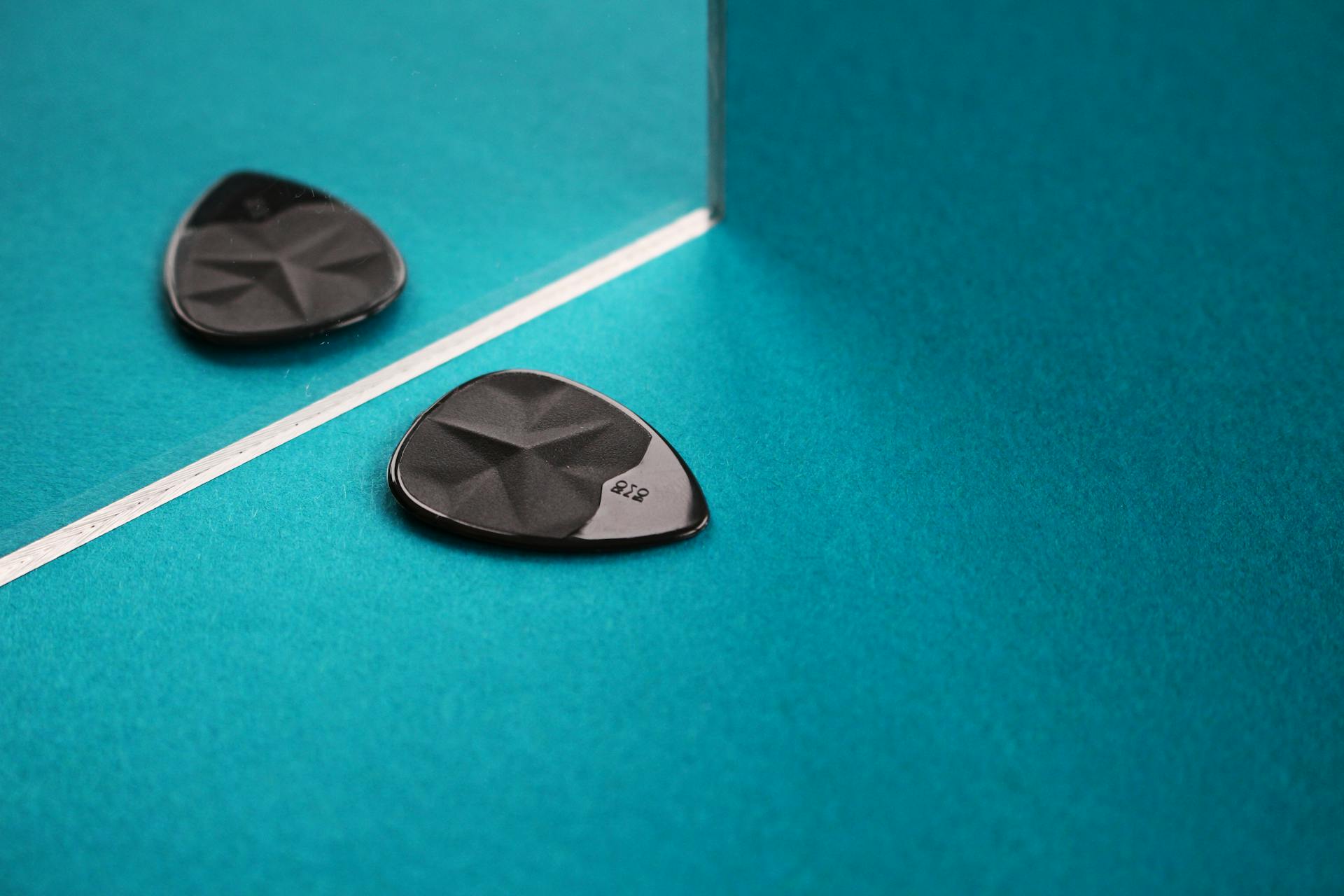 Black Guitar Pick in Front of a Mirror