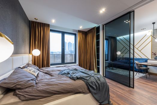 Bedroom interior with unmade bed near glass door and window