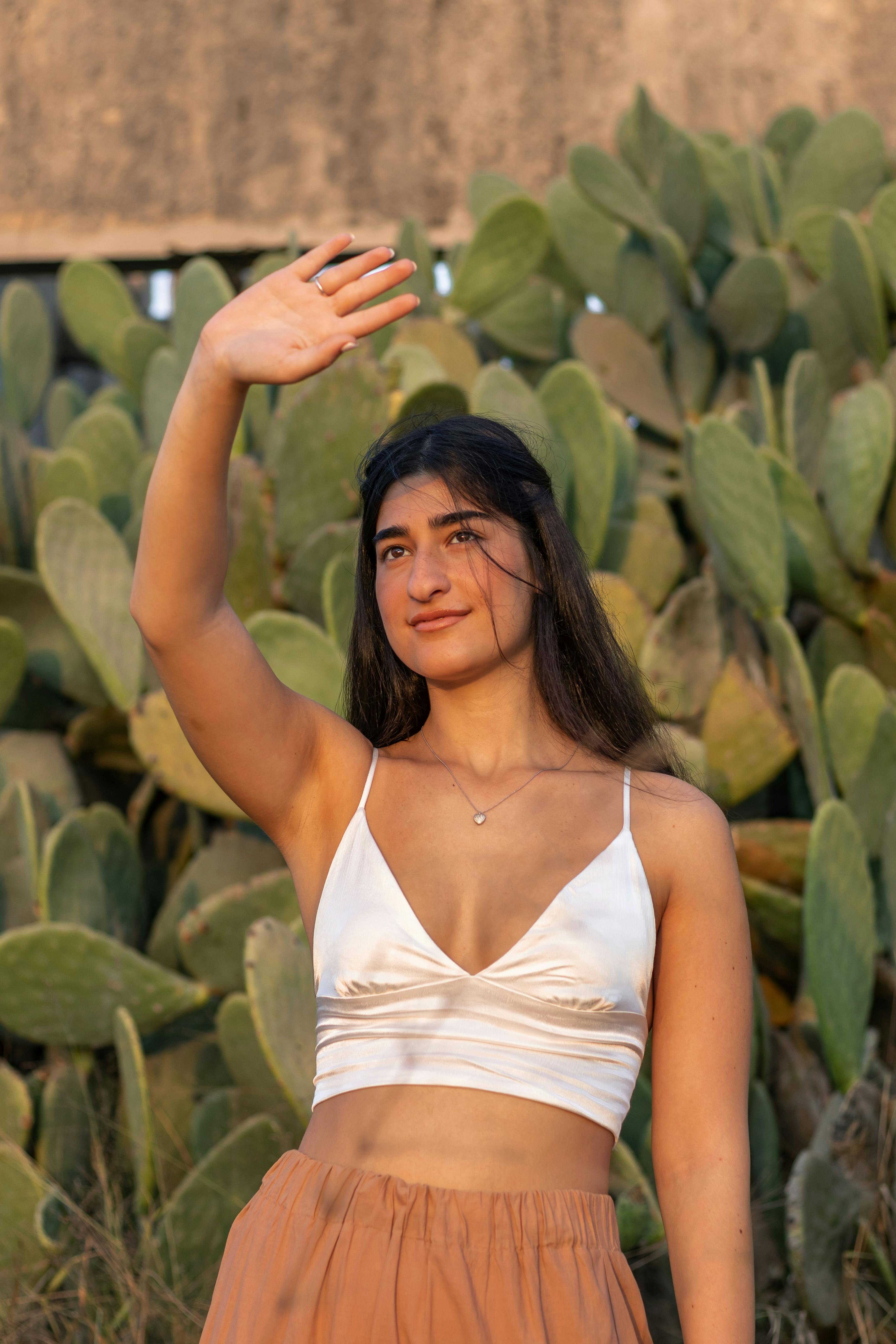 a woman in white crop top standing near cactus plants