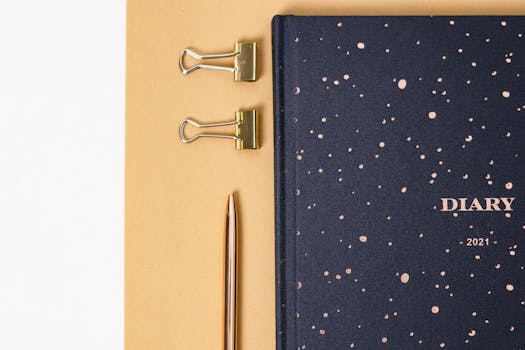 Top view of a 2021 diary with binder clips and pen on a beige background.
