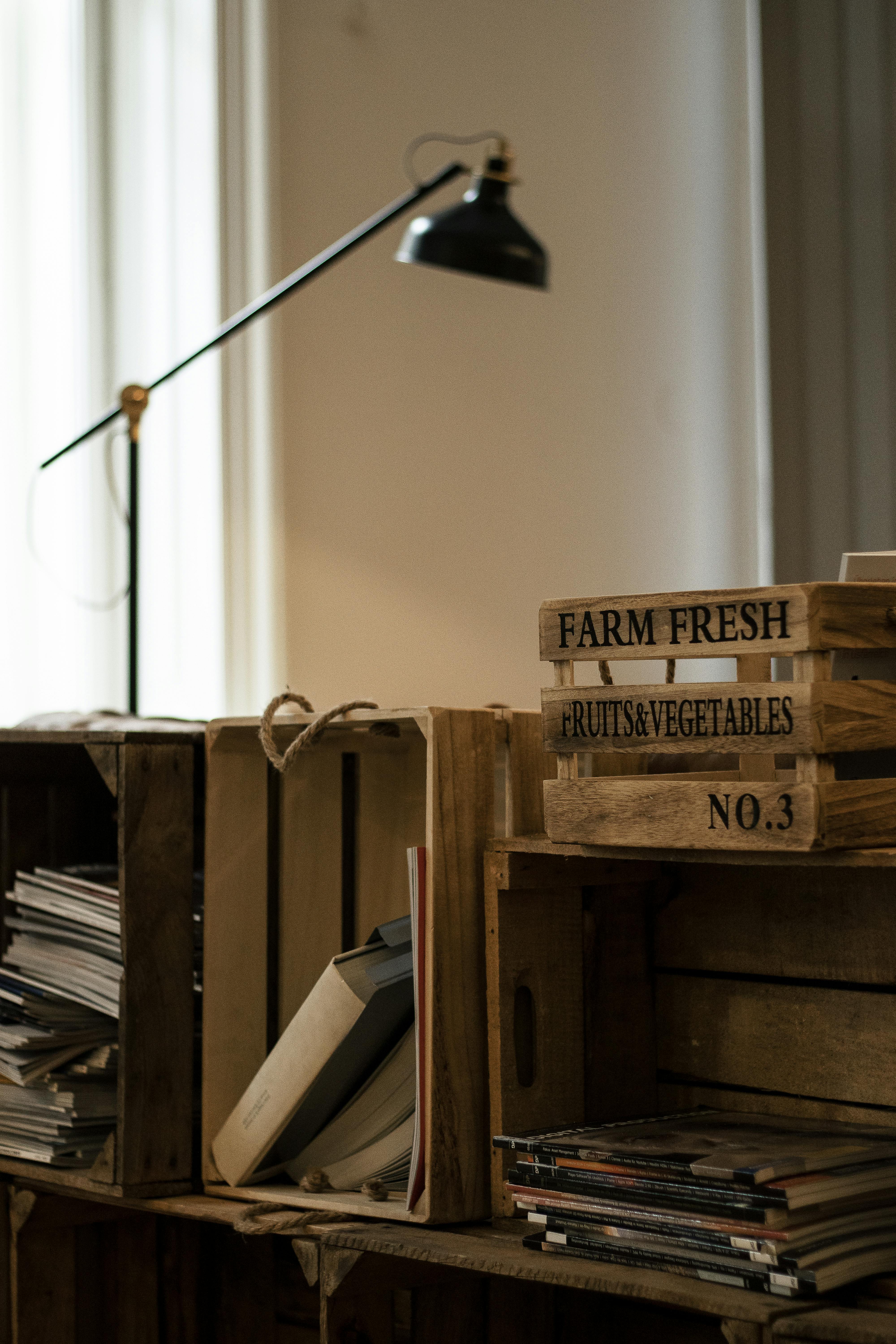 Free Cozy room with wooden crates, books, and a vintage lamp, ideal for a rustic home aesthetic. Stock Photo
