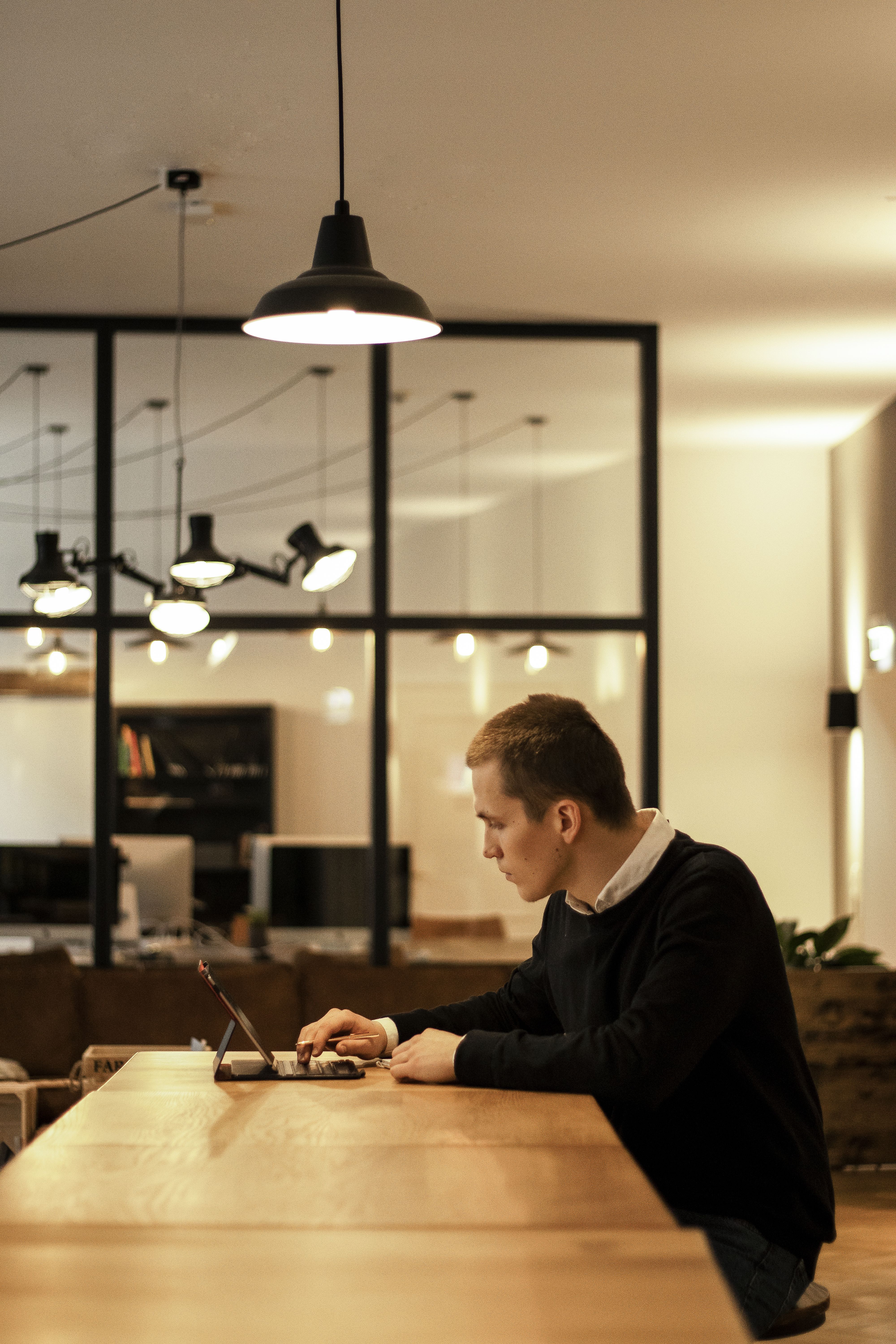A focused businessman working on a laptop in a modern open office environment.
