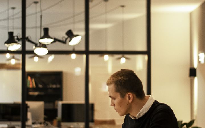 A focused businessman working on a laptop in a modern open office environment.