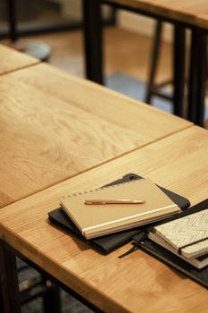 A close-up shot of notebooks and a pen on a wooden desk, perfect for education themes.