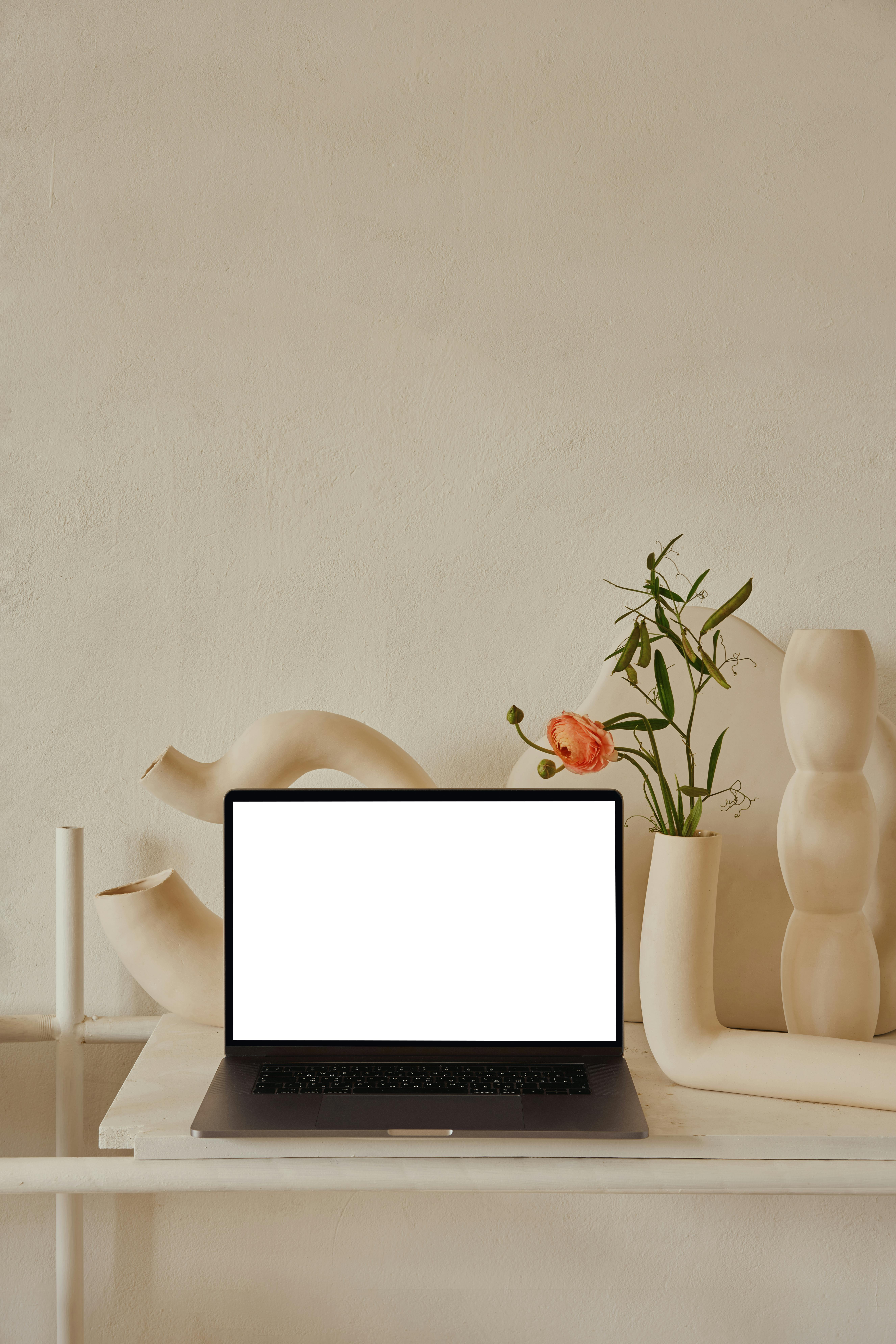 laptop on shelf near decorative ceramic vases with flowers