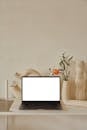 Laptop on shelf near decorative ceramic vases with flowers
