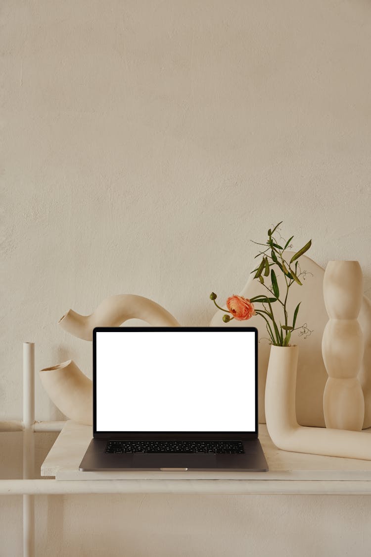 Laptop On Shelf Near Decorative Ceramic Vases With Flowers