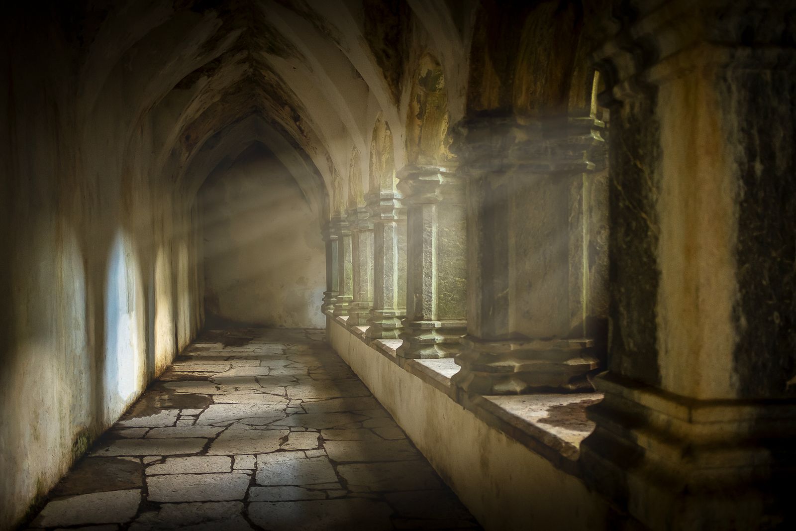 Sunlight streams through an ancient Gothic corridor in Killarney, Ireland, illuminating stone arches