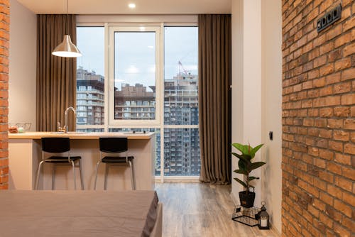 Contemporary apartment interior with bed and kitchen counter and overlooking floor to ceiling window