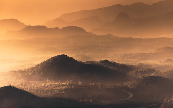 Sunrise view of misty mountain ranges in Santa Cruz de Tenerife, creating a dramatic silhouette with a warm, scenic ambiance.
