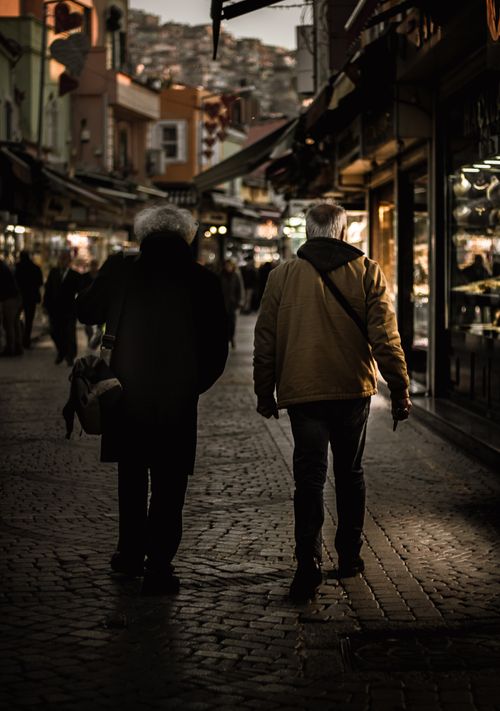 Free Two people walking through a lively downtown street market during evening hours. Stock Photo