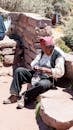 Elderly Man Sitting on Ground Sewing Hat