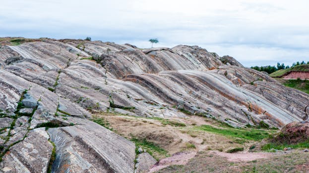 Explore a peaceful rocky hill landscape with a solitary tree under a serene sky.