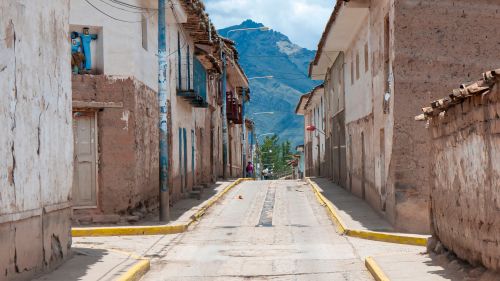 Free Discover the rustic charm of a narrow street in a traditional Peruvian town surrounded by stunning mountains. Stock Photo