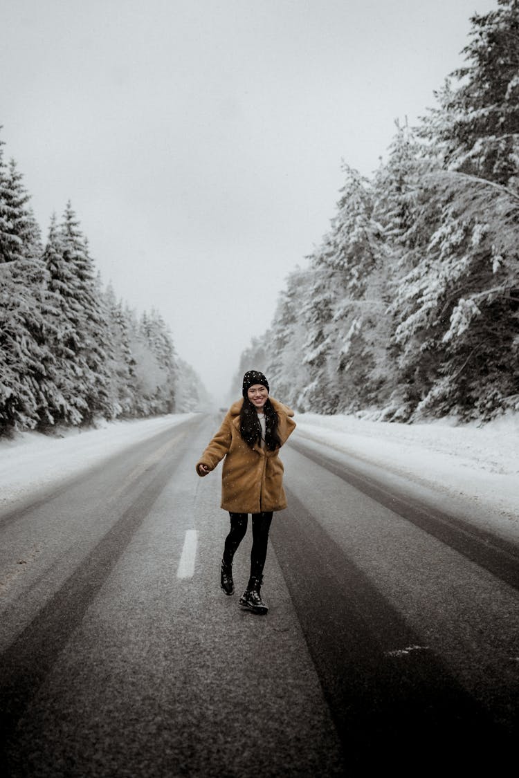 Smiling Woman Running On Road In Winter Forest