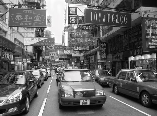 Free Black and white street view of busy urban life in downtown Hong Kong with taxis and signages. Stock Photo