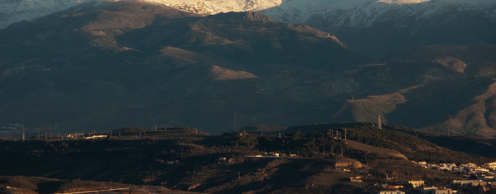 Breathtaking view of snowcapped mountains with a city in the valley, captured at daytime.