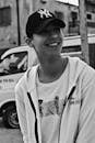 Grayscale Photo of a Man with Cap Smiling