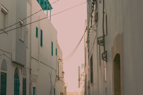 Free A picturesque view of a narrow urban street with white houses, captured at twilight. Stock Photo