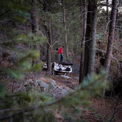 A Man Standing on the Old Car in the Forest