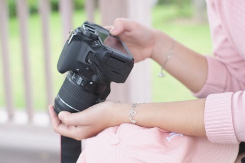 Close-Up Shot of a Person Holding a Black DSLR Camera