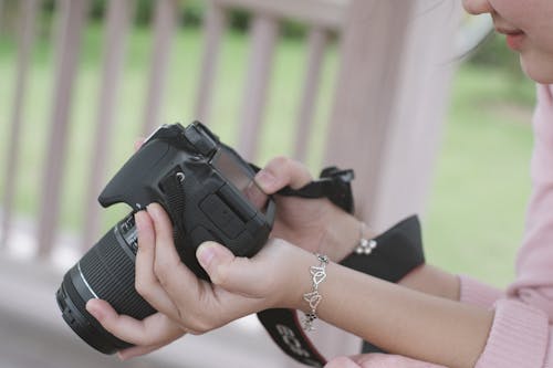 Close-Up Shot of a Person Holding a Black DSLR Camera