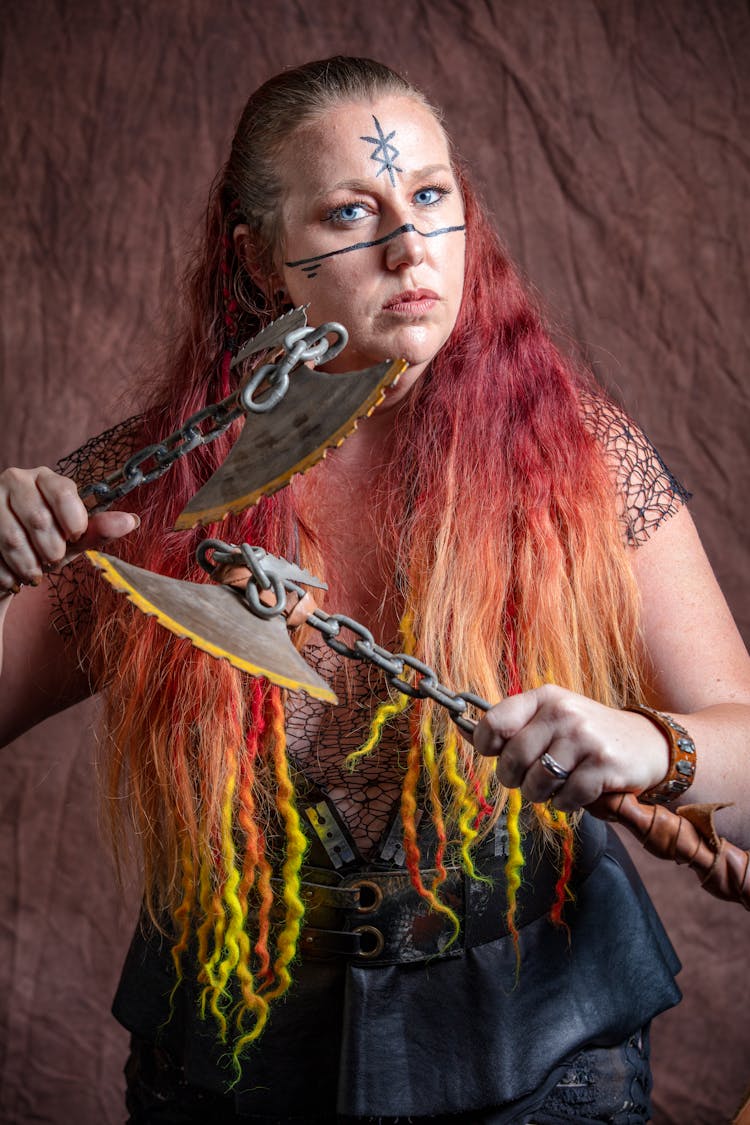 Woman In Viking Costume With Facial Tattoos Holding Axes