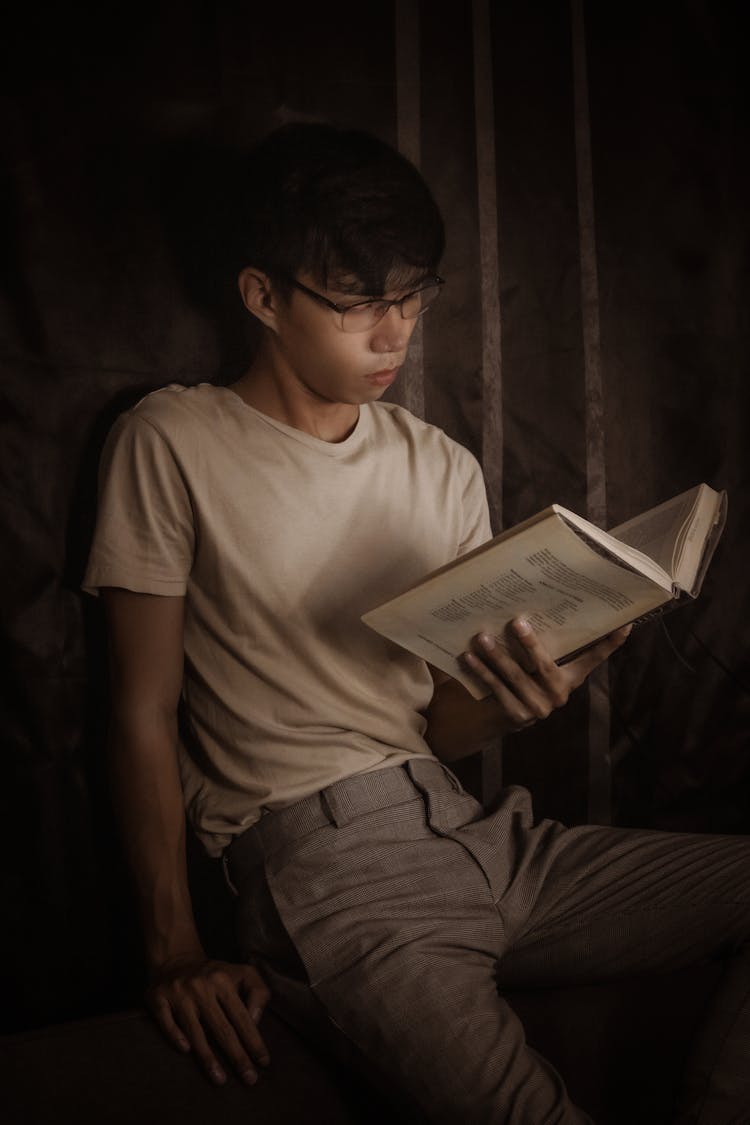 Pensive Man Reading Book In Dark Room