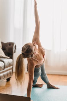 Full body side view of side plank asana on mat near laptop during online yoga lesson in living room