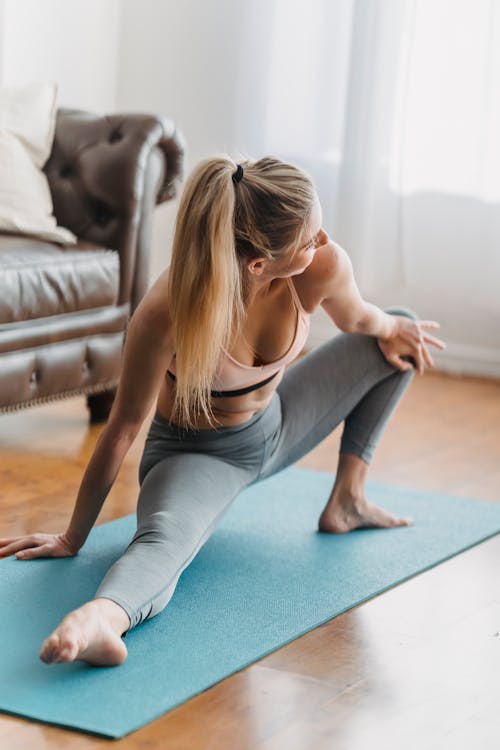 Wanita Dengan Tank Top Abu Abu Dan Jeans Denim Biru Duduk Di Atas Matras Yoga Biru