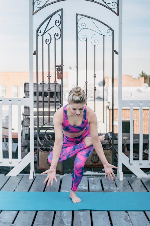 Full body of concentrated female in activewear performing Eka Pada Utkatasana during yoga session on sports mat