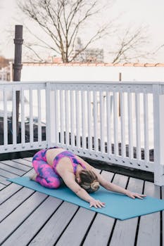A woman in vibrant activewear performs yoga on an outdoor terrace, embracing wellness and mindfulness.