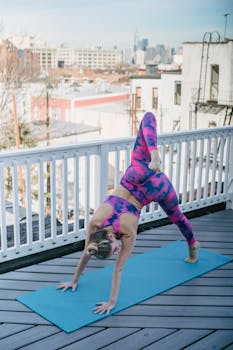 Woman in colorful activewear doing yoga on a mat with urban skyline view.