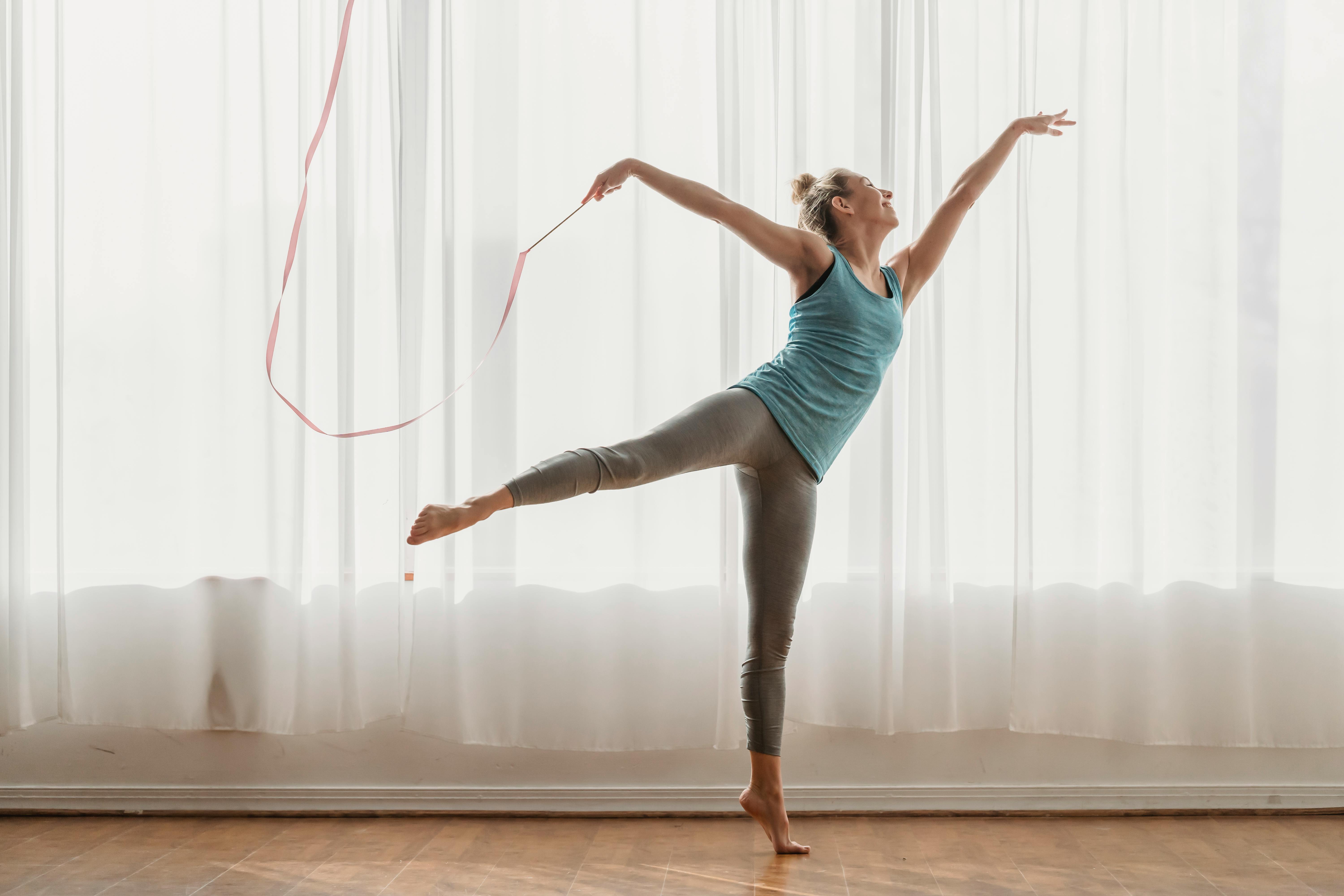 flexible woman dancing with ribbon in swallow pose