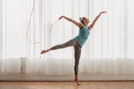 Flexible woman dancing with ribbon in swallow pose